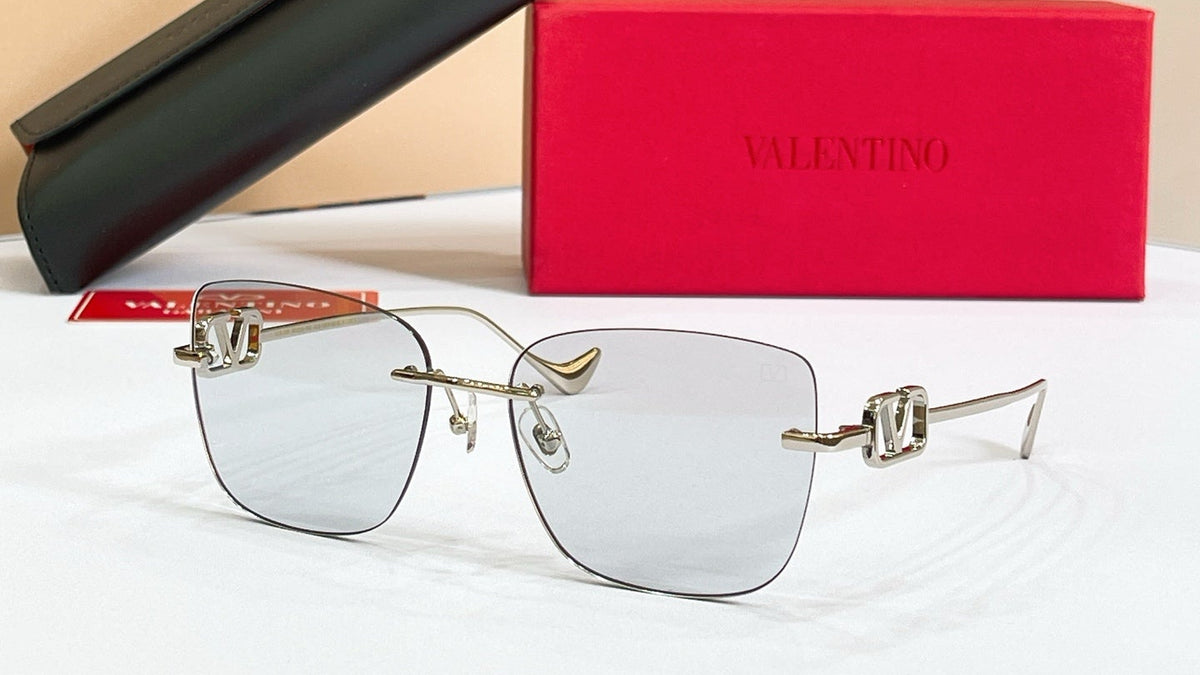 Valentino sunglasses with black case and red box on a beige background