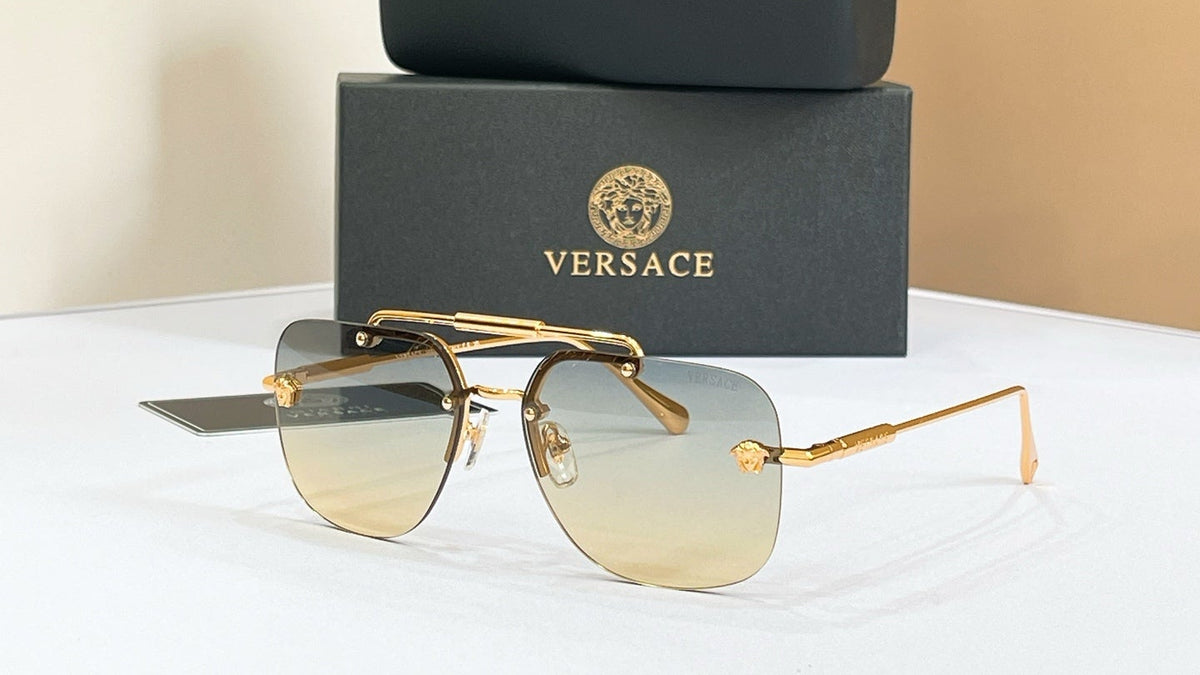 Versace gold-frame sunglasses with gradient lenses on a white surface